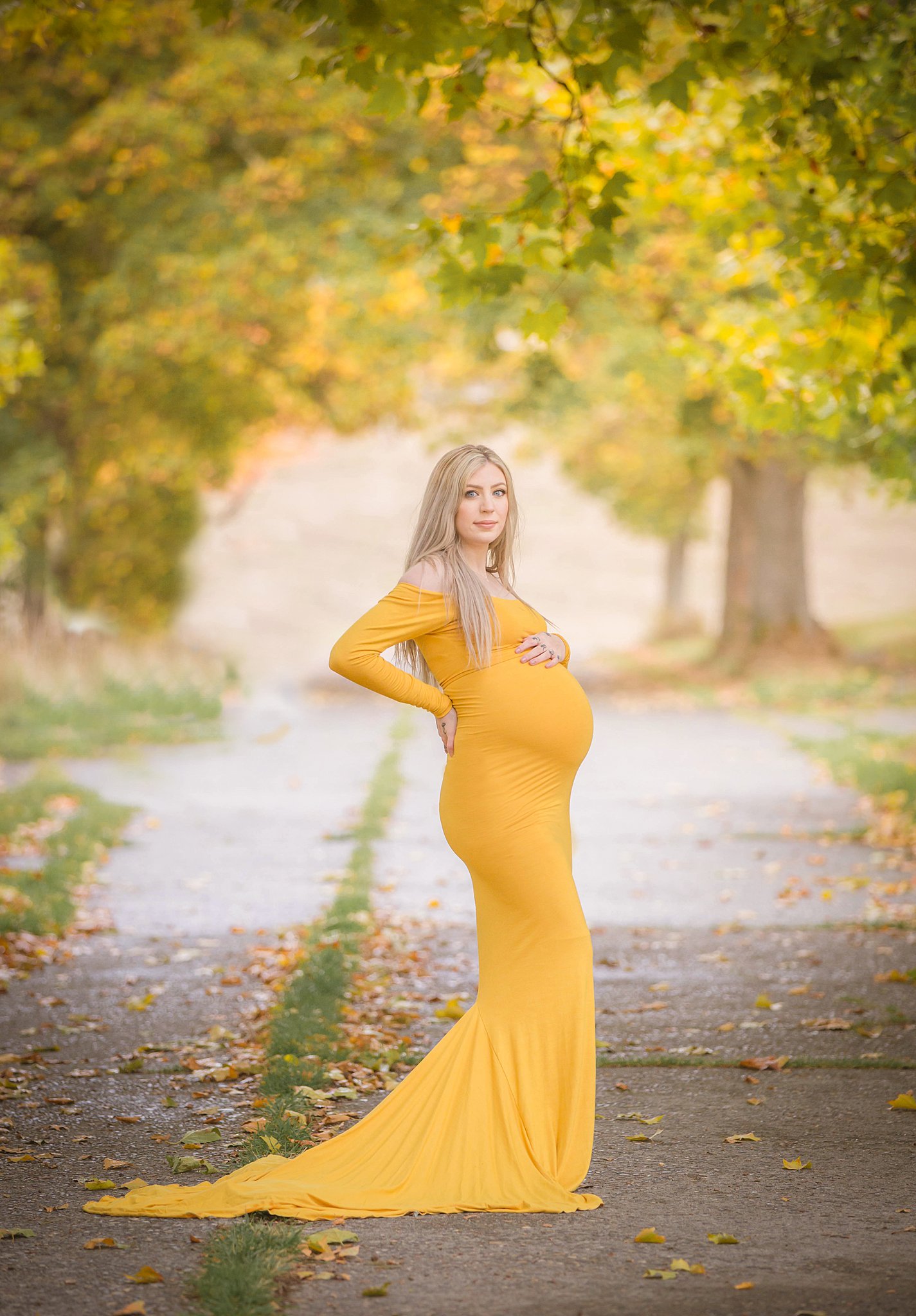 mother to be stands in a yellow maternity gown in a park sidwalk Seattle Midwife